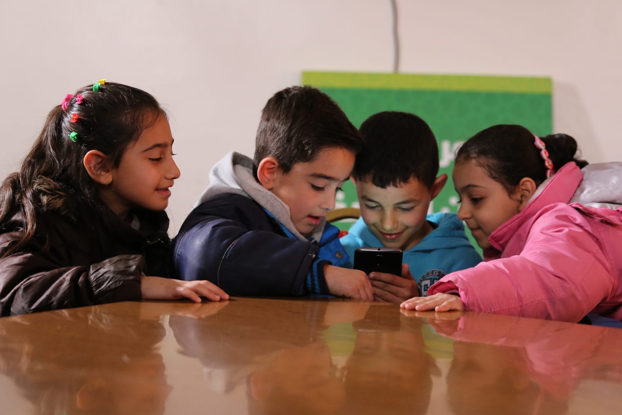 A group of Syrian refugee children in Jordan play the Feed the Monster literacy gaming app sourced through the EduApp4Syria prize.