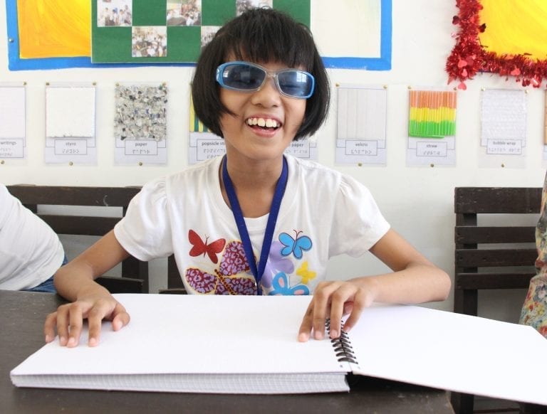 Alexa, a blind student in the Philippines, smiles as she reads a braille book provided through Resources for the Blind's "Reading Beyond Sight" project.