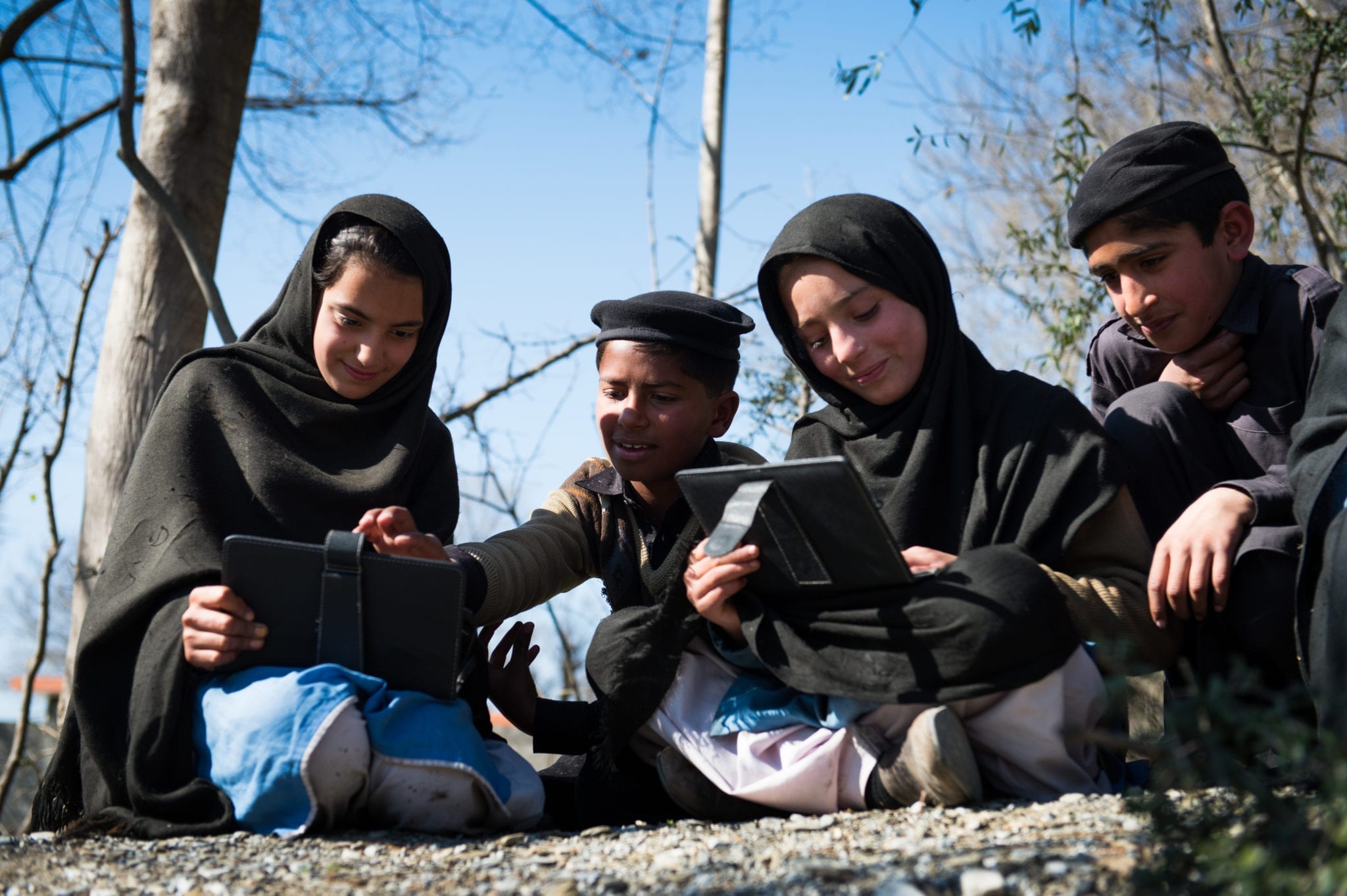 A group of children learn via tablet devices.