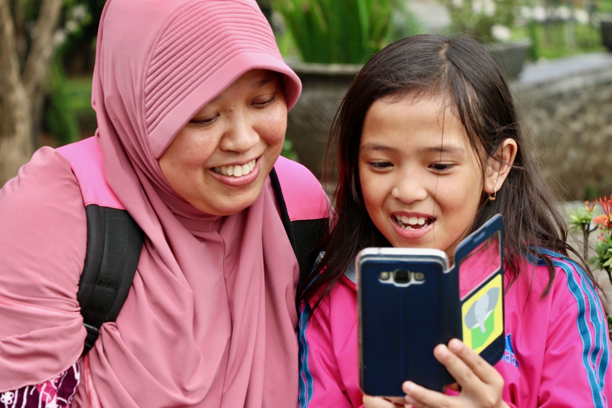 A mother and daughter enjoy stories on a mobile phone provided by ACR GCD-funded The Asia Foundation.
