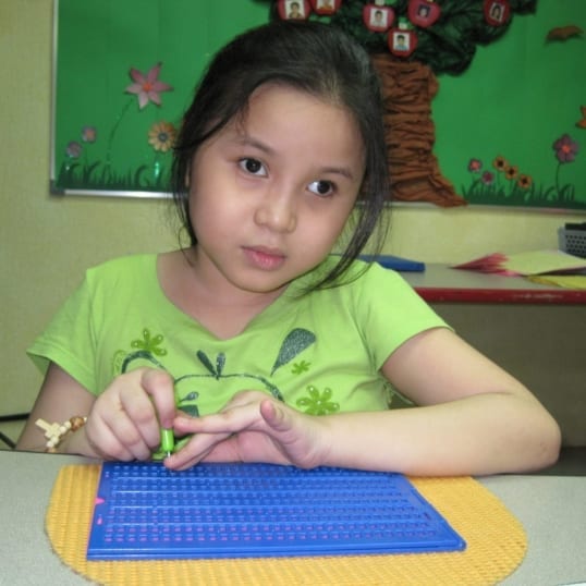 A girl with blindness in the Philippines uses a braille reader supplied through the ACR GCD-funded Reading Beyond Sight project by Resources for the Blind, Inc.
