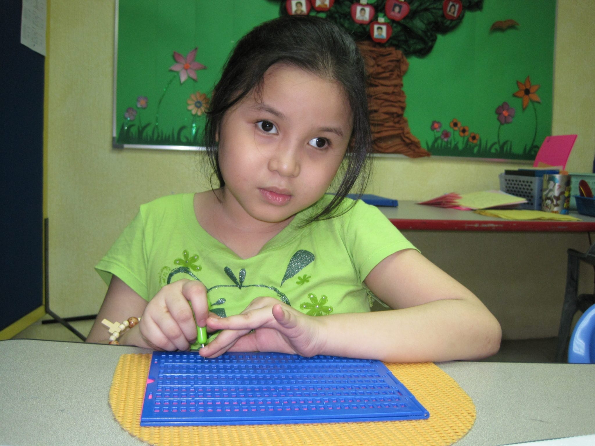 A girl with blindness in the Philippines uses a braille reader supplied through the ACR GCD-funded Reading Beyond Sight project by Resources for the Blind, Inc.