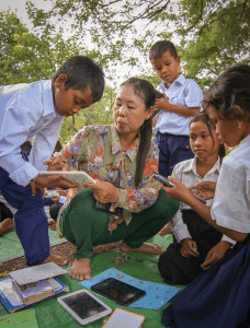 A teacher in Cambodia helps a group of children learn on a tablet-based literacy learning app in the local language of Khmer.