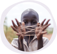 a child holding a cats cradle between their fingers