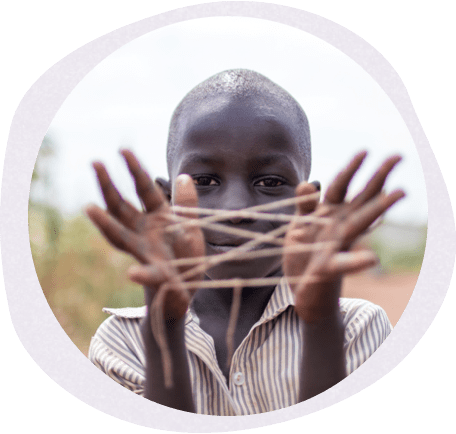 a child holding a cats cradle between their fingers