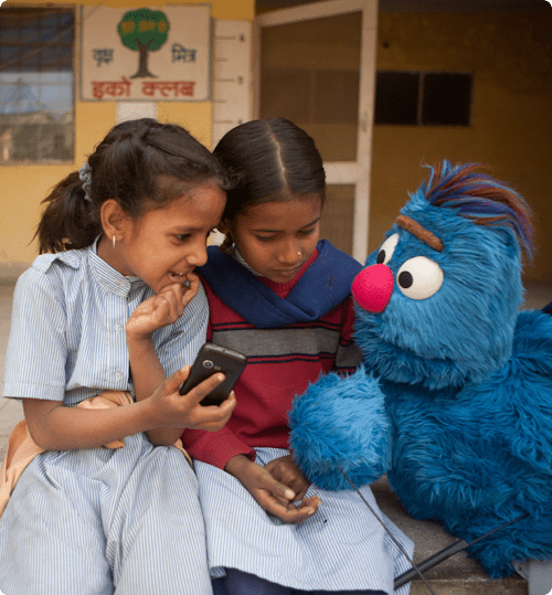 Two girls talking to a muppet