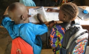 Two African children read a local language book provided by SIL LEAD.