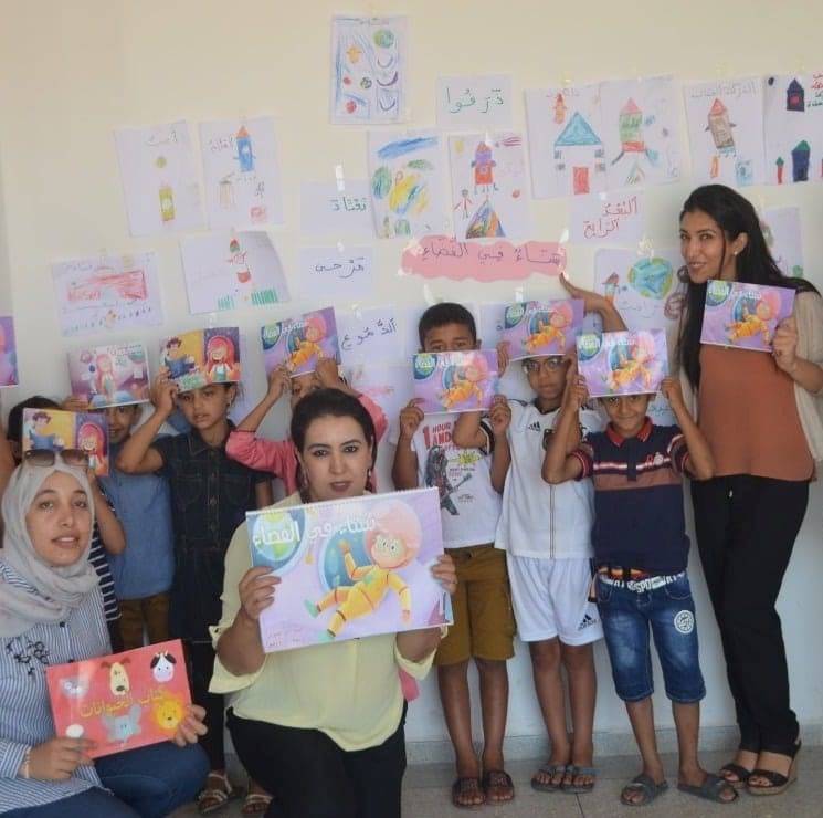 Children hold up STEM-themed books written in Arabic by ACR GCD prize winner Asafeer.
