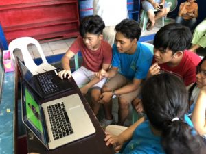 Children gathered around a laptop using the WAY digital library platform