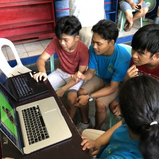 Children gathered around a laptop using the WAY digital library platform