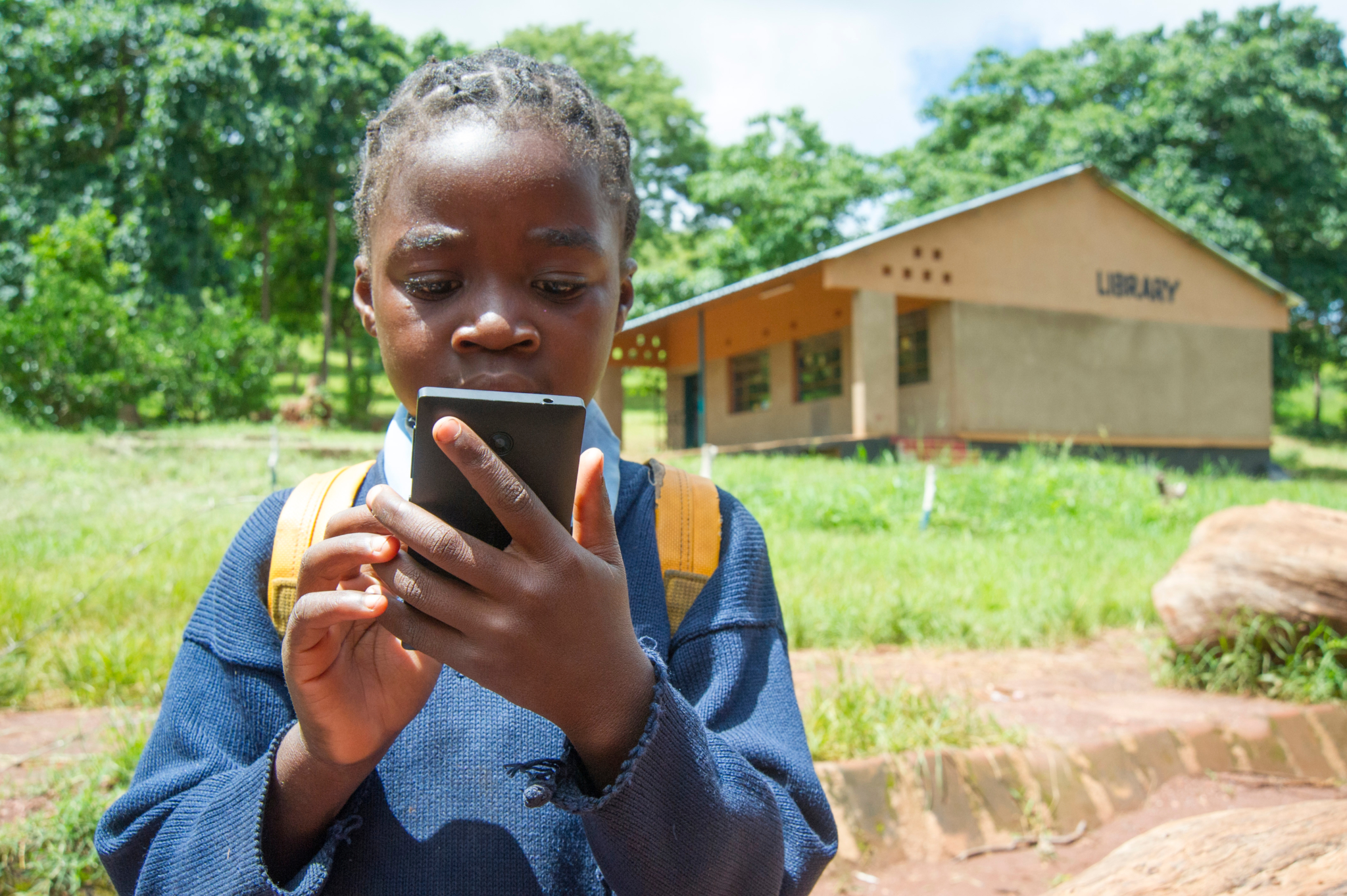 A youth using a mobile phone on the grounds of the Katopola School just outside of Chipata - one of the more than 1,100 schools taking part in the Read to Succeed project.