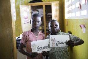 Two children holding drawings of sign language images
