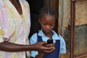 A youth using a mobile phone in Chipata, Zambia, where Creative Associates International mobilized community members to submit favorite local stories and folktales and distributed the stories, along with comprehension questions, to early grad students their families via SMS.