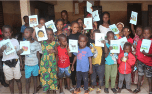 A group of children holding up printed copies of digital books at a school.